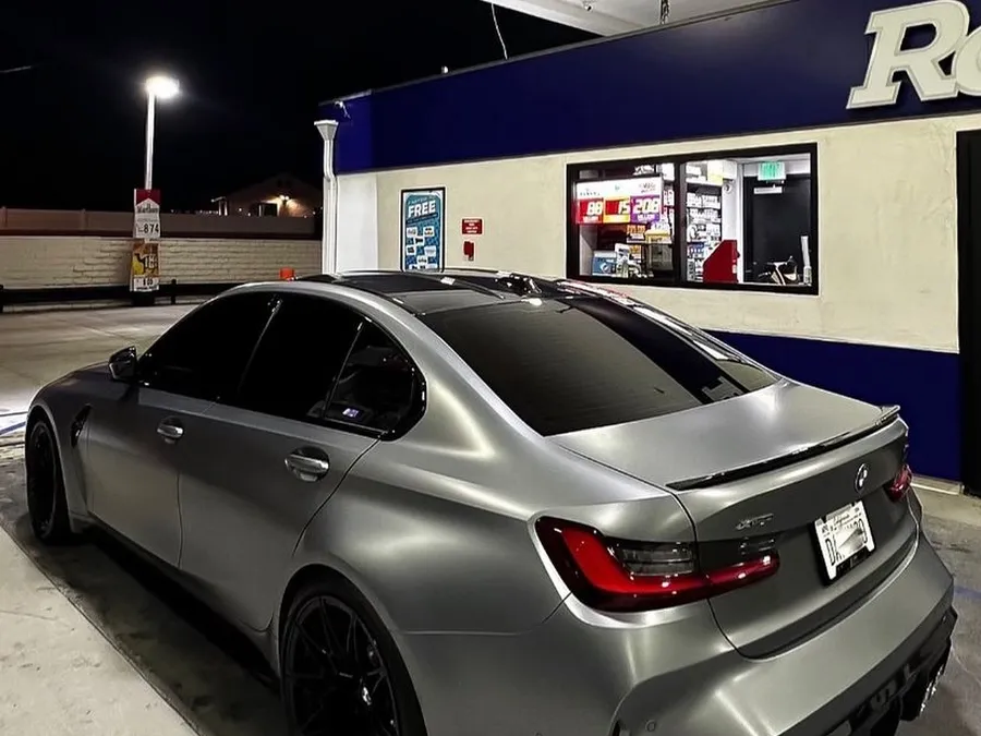 Grey sedan with fresh ceramic tint outside the shop at night